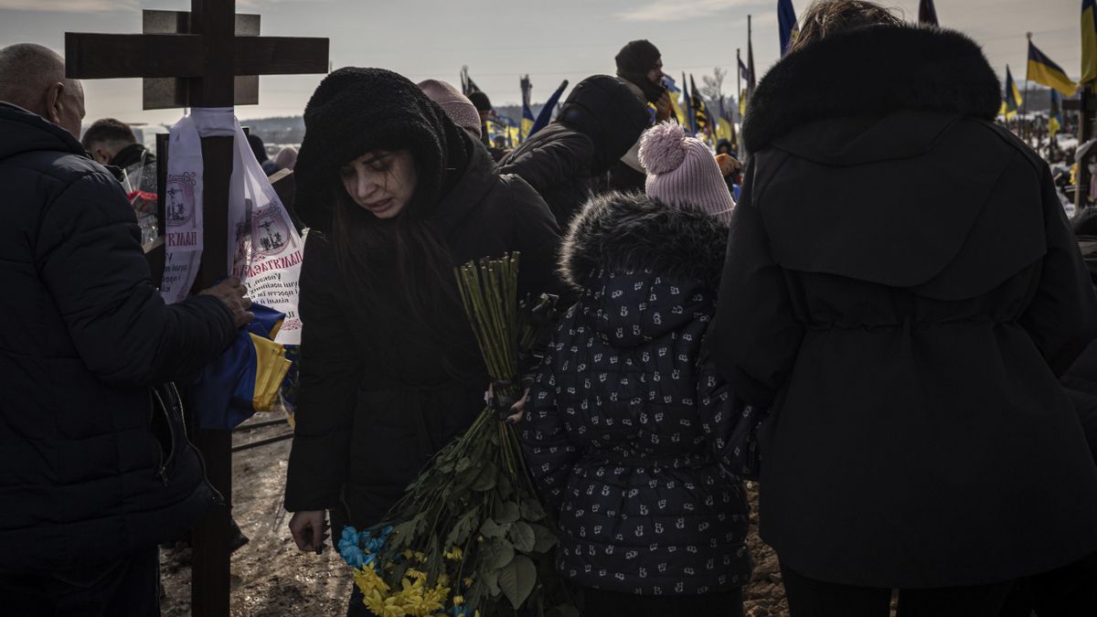 Familiares de un soldado caído asisten a su funeral en el cementerio número 18 de Járkov en vísperas del cuarto aniversario de la invasión rusa.