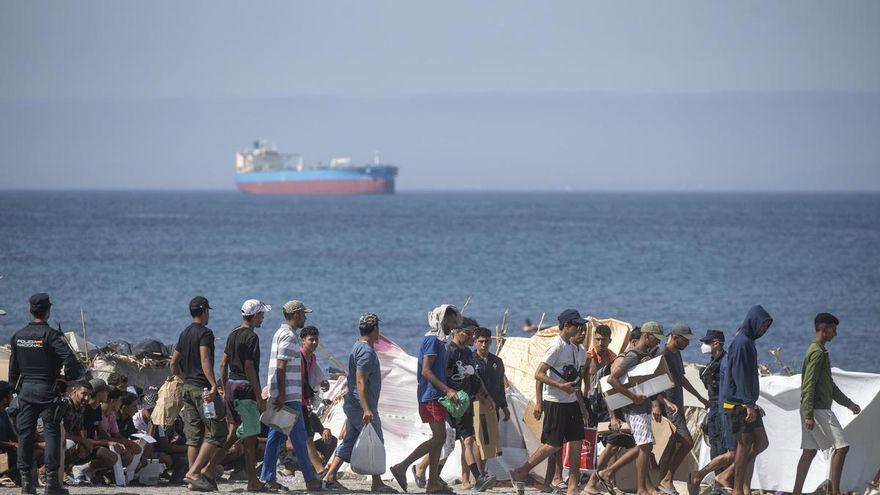 Decenas de migrantes caminan por la playa del Trampolín, en Ceuta