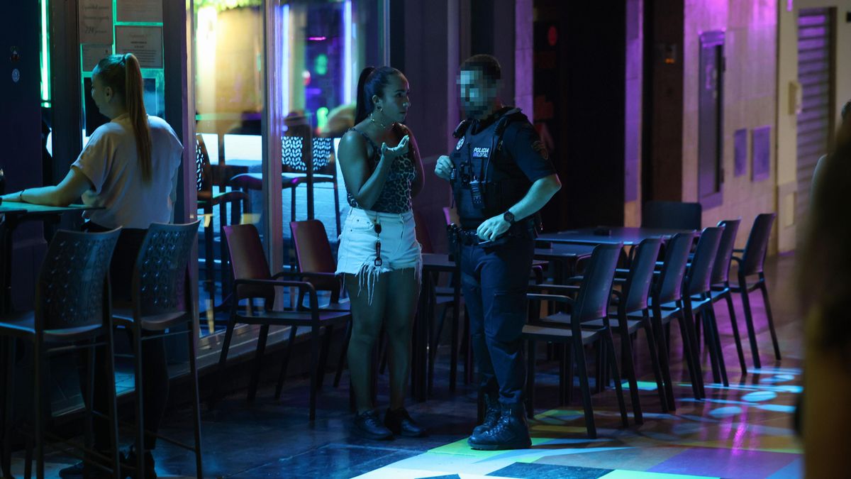 Una dona parla amb un Policia Local al carrer Santa Agnès, que l'Ajuntament ha intentat reconvertir amb l''Arcoiris Infinito' d'Okuda