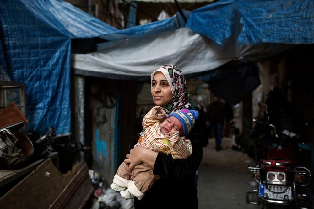 Iman, madre de 4 hijos, sostiene a uno de sus bebés a las puertas de la unidad de maternidad de MSF en el campo de Shatila. Ha vivido refugiada en el Líbano durante los últimos tres años, después de haber huido de la guerra en Siria. Acude a la unidad de maternidad con regularidad para hacer un seguimiento de su bebé. “No tenemos nada. Mi esposo no tiene trabajo estable y luchamos cada mes para poder sobrevivir”. Fotografía: Diego Ibarra Sánchez