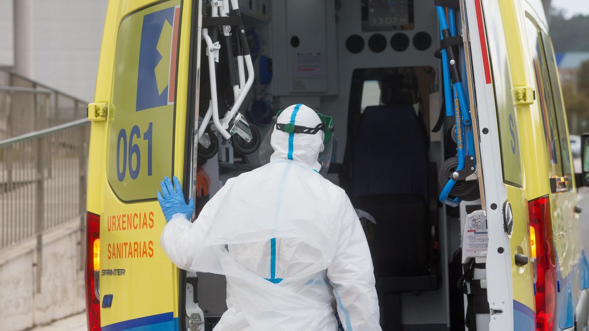 Un trabajador sanitario totalmente protegido cierra la puerta de una ambulancia