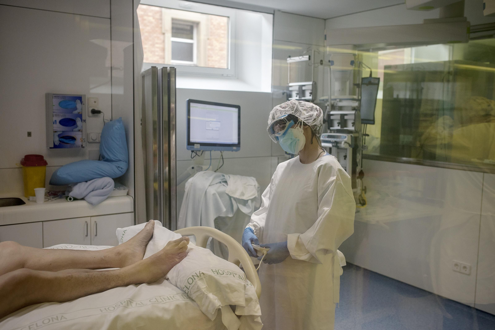 Una enfermera de la AVI reclina la cama de su paciente con un control remoto. Esta Unidad de Cuidados Intensivos especializada en enfermedades infecciosas ha tenido que ampliarse a otras zonas del hospital que se utilizaban para otro tipo de casos.