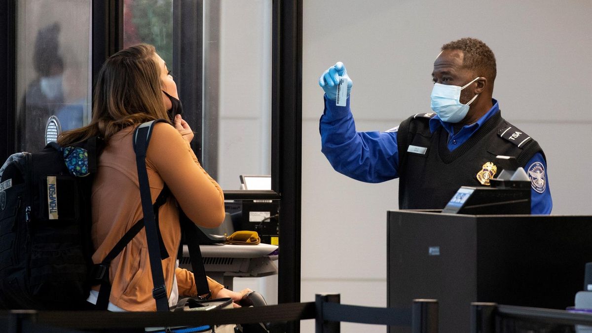 A Transportation Security Administration (TSA) employee checks the identification of a traveler going through security at Ronald Reagan Washington National Airport in Arlington, Virginia, USA, 27 December 2021. Thousands of flights across the globe were cancelled over the Christmas weekend and continued 27 December, sparked by the omicron variant of Covid-19.