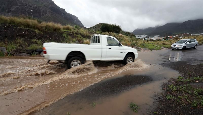 Un vehículo atraviesa una carretera inundada por las lluvias en el municipio de La Aldea de San Nicolás