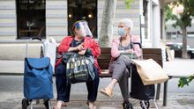 Dos mujeres con mascarillas sentadas en un banco