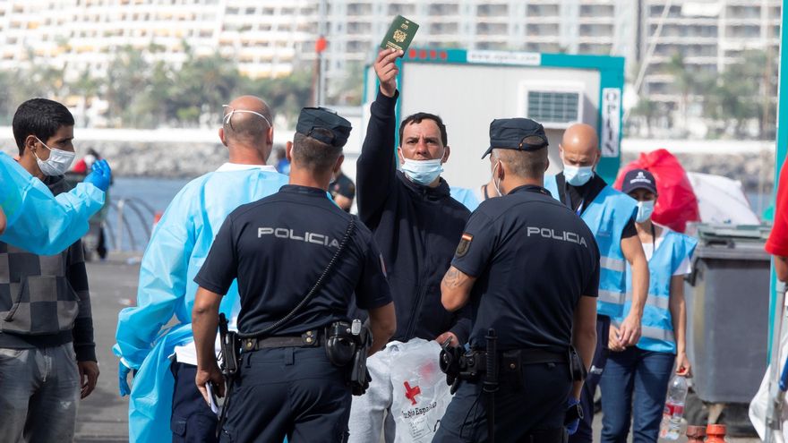Un hombre muestra su pasaporte desde dentro del muelle de Arguineguín