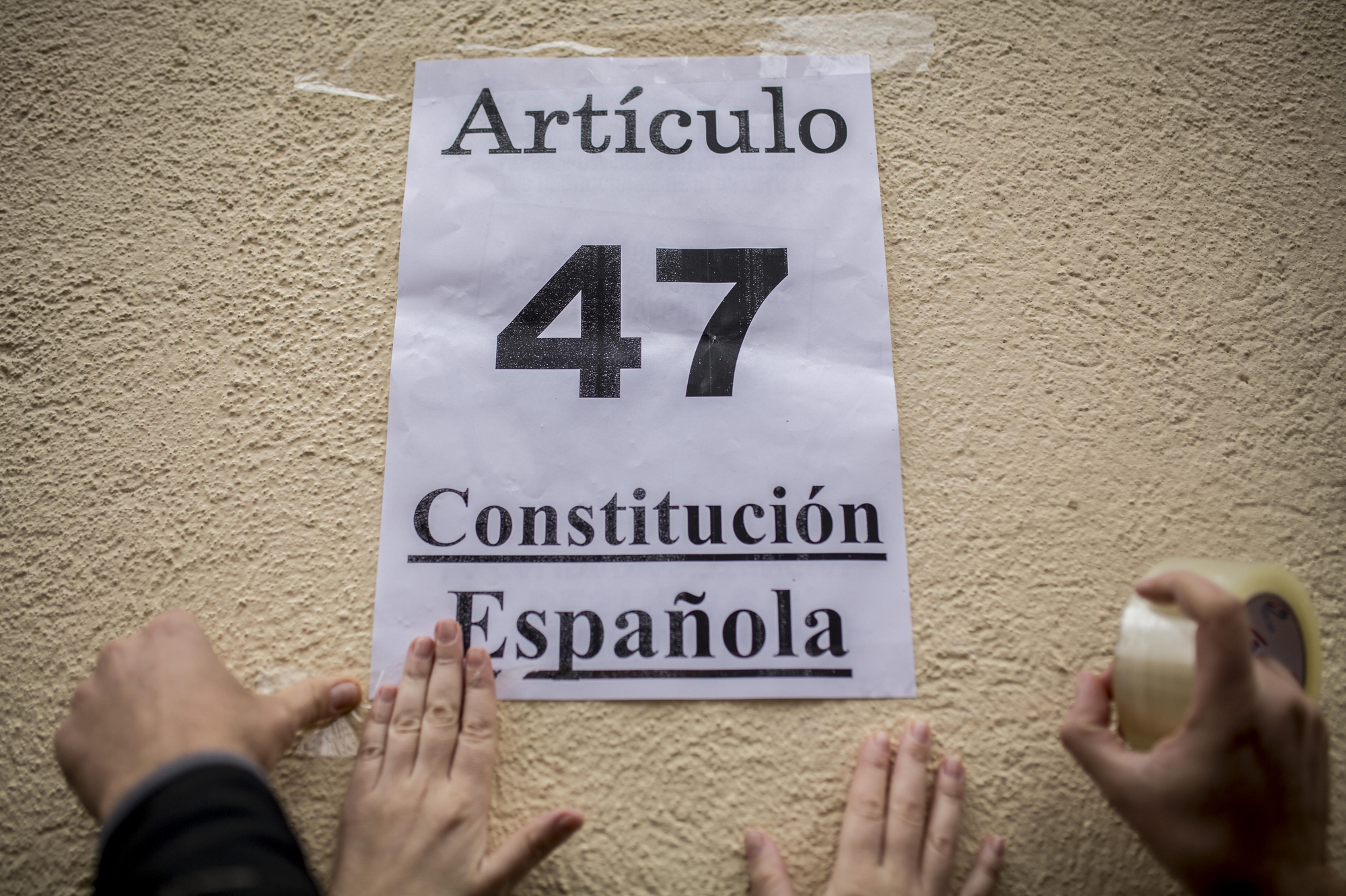 Activistas por el derecho a la vivienda pegan un cartel en el que puede leerse "Artículo 47 Constitución Española" en el exterior de un edificio donde está previsto un desahucio, en enero de 2011