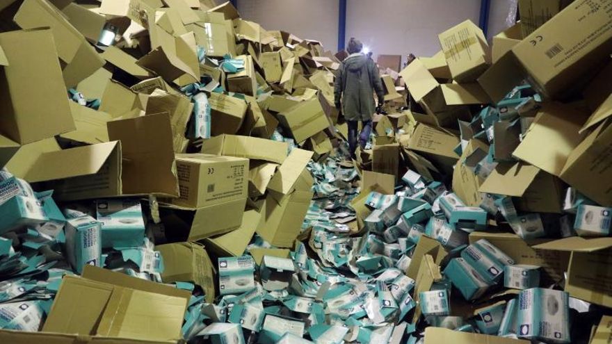 Un fotógrafo camina entre las cajas de material sanitario almacenado en el interior de una nave del polígono del Tambre en Santiago de Compostela, durante la redada policial de ayer para descubrir el robo de cerca de dos millones de mascarillas y otro material sanitario, valorado en cinco millones de euros.