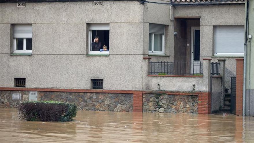 Unos vecinos observan desde su casa el río Ter, que se ha desbordado a su paso por la ciudad de Girona, en el punto más bajo de su recorrido, junto a la carretera C-255, más allá del puente del Agua este miércoles.