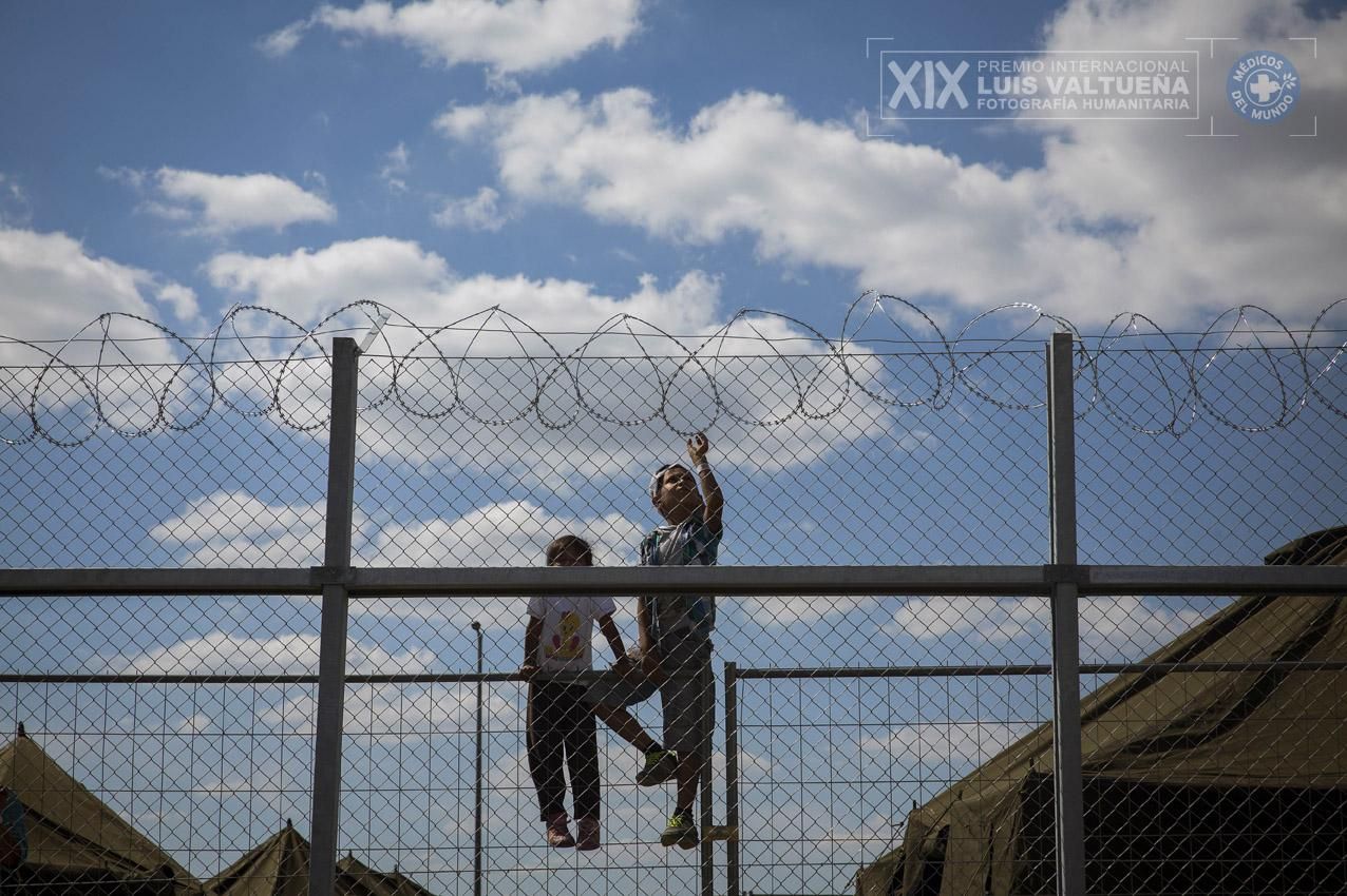 Un niño y una niña subidos a una valla en el interior del campo de refugiados de Roszke, en Hungría. En ese momento, el Gobierno húngaro dirigía a todos los refugiados a campos similares donde podían permanecer días encerrados mientras les identificaban hasta que les dejaban continuar su camino. (Roszke. Hungría. 09/09/2015). | Foto: Olmo Calvo.