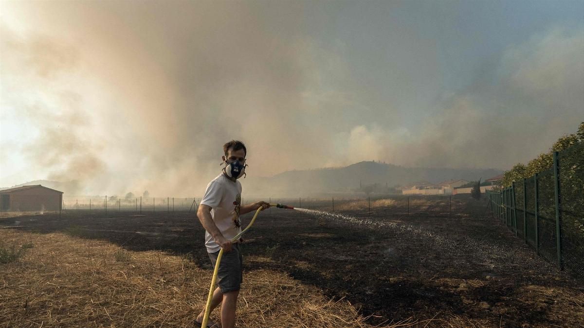 Un vecino riega el campo para evitar la propagación del fuego en el sur de Francia
