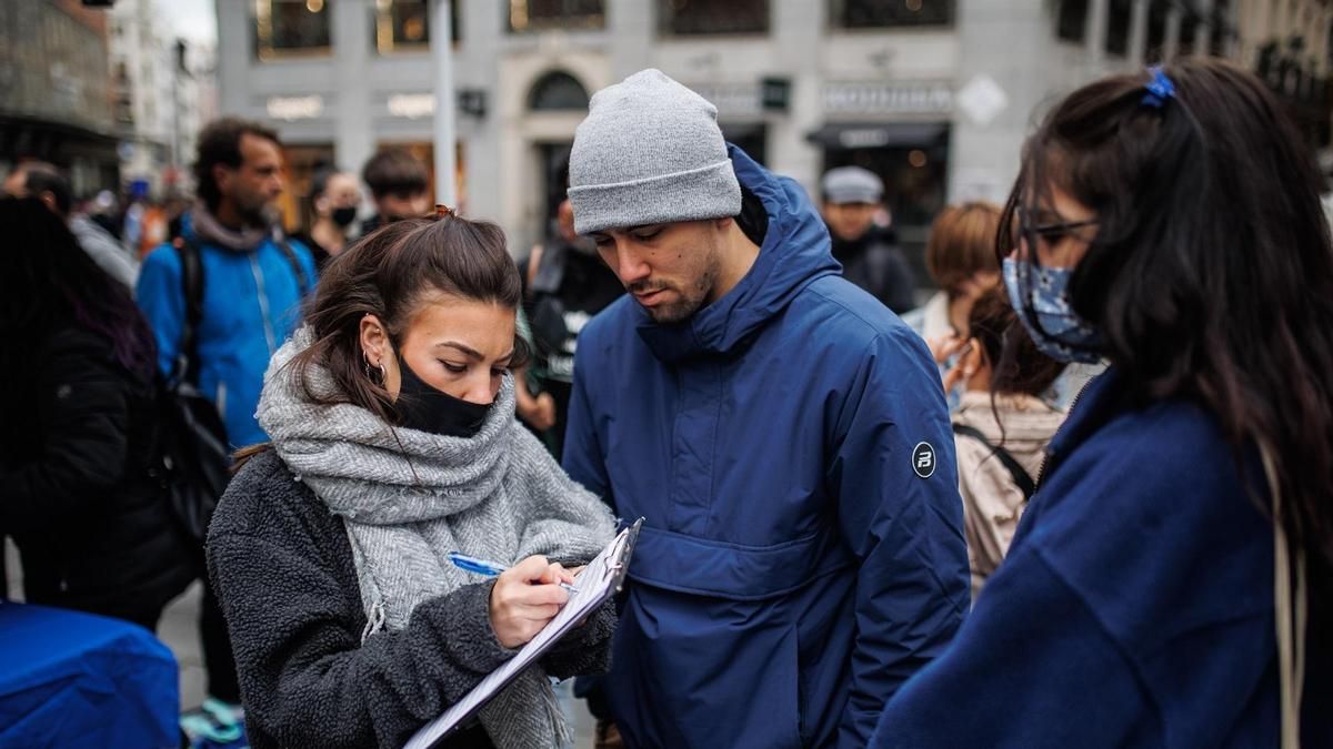 Un grupo de personas recoge firmas para pedir la regularización de las personas migrantes en febrero de 2022, Madrid
