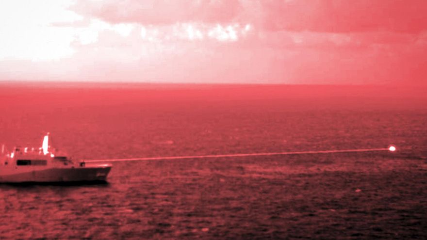 El buque de transporte anfibio USS Portland lleva a cabo una demostración del sistema de armas láser de alta energía sobre un objetivo de entrenamiento estático en la superficie en el Golfo de Adén, el 14 de diciembre de 2021.