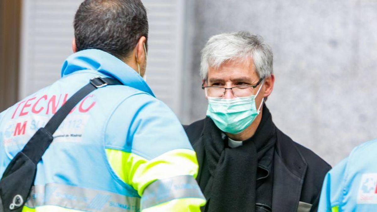 Un técnico sanitario habla con un sacerdote en el interior de un hospital público que atiende a pacientes COVID