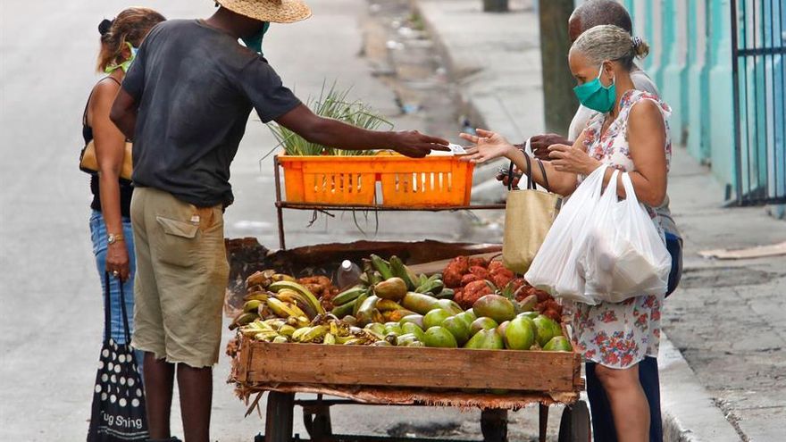 na mujer con mascarilla compra verduras a un vendedor ambulante, en La Habana (Cuba).