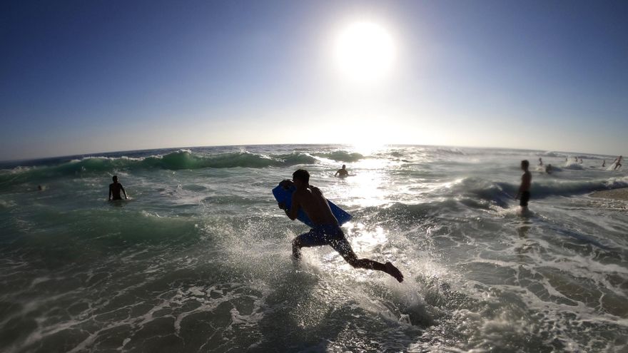 Un surfero corre hacia el agua en la playa de Windansea en La Jolla, San Diego, California.