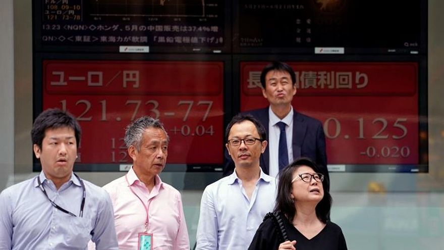 Peatones caminan junto a una pantalla que muestra información bursátil en Tokio (Japón).