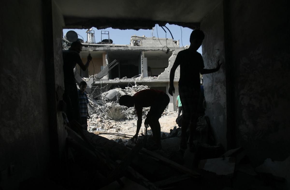 Unos jóvenes recorren las ruinas de su casa destruida en Rafá, Gaza, buscando algo que se pueda salvar. Foto Eyad Al Baba/Zuma Press.