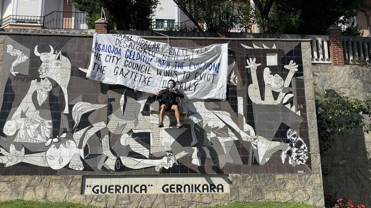 Un joven se cuelga del mural del 'Guernica' en Gernika para defender el 'gaztetxe'