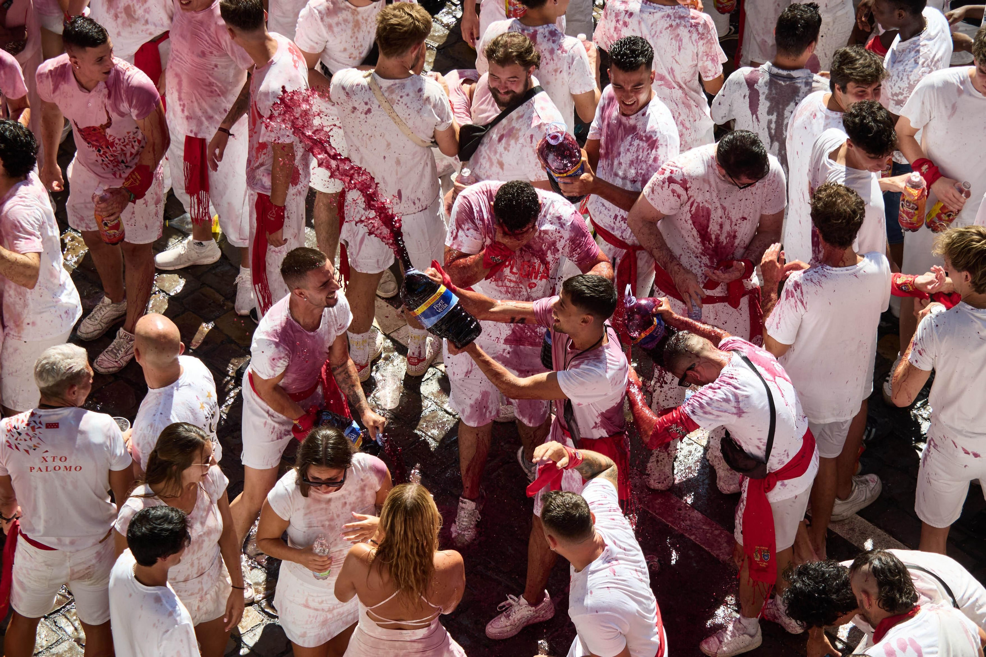Grupos de amigos comparten bebidas en la Plaza del Ayuntamiento durante las fiestas de San Fermín