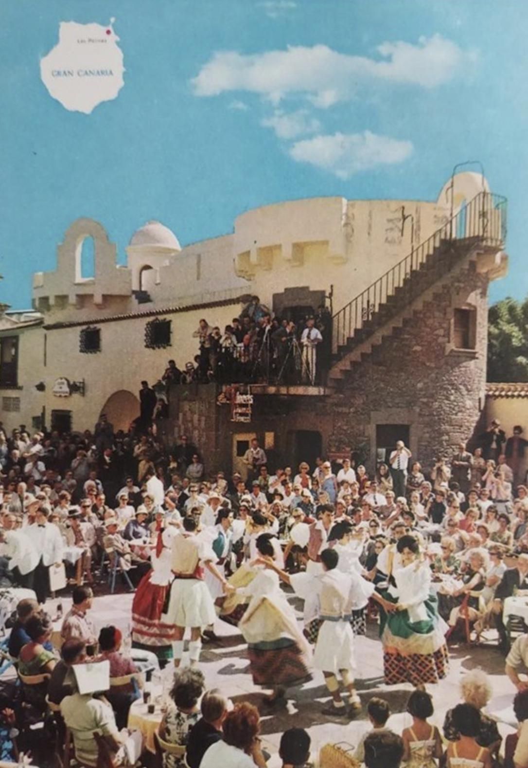 Postal de actuaciones folclóricas en el Pueblo Canario. En el fondo, los torreones que albergan al CIT y la Oficina de Turismo.