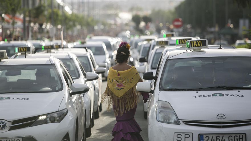 Una flamenca circula entre taxis en la parada habilitada en la Feria de Abril.