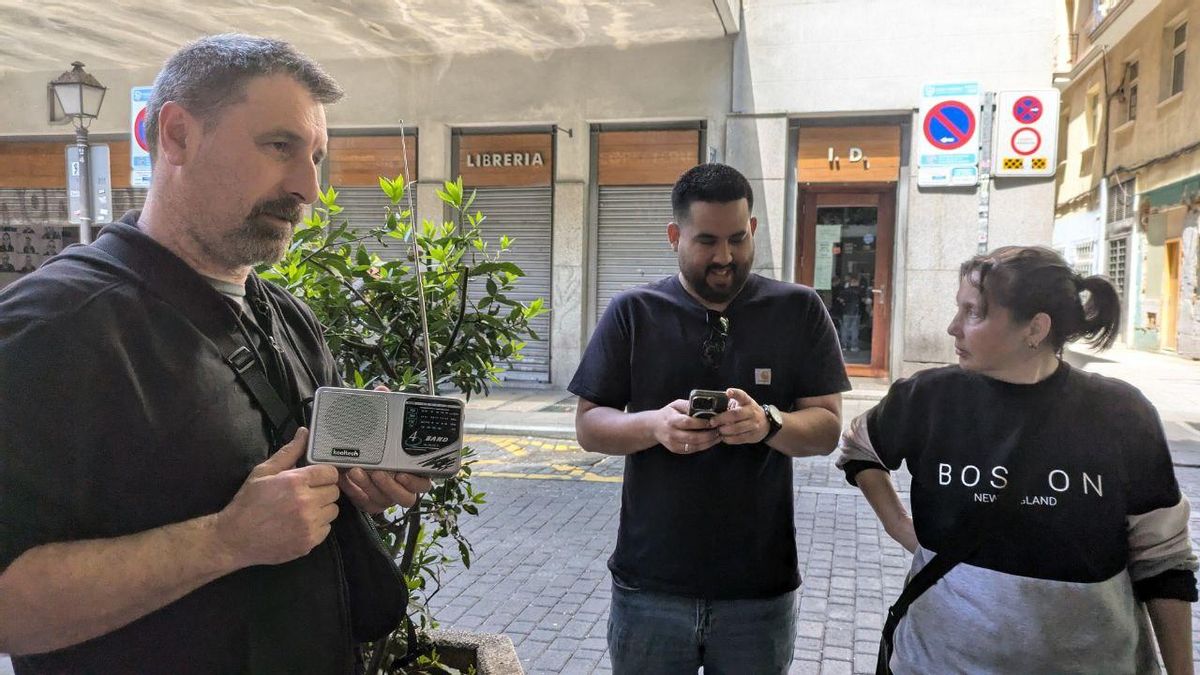 Varias personas, en Lavapiés, escuchando un transistor de radio durante el apagón.