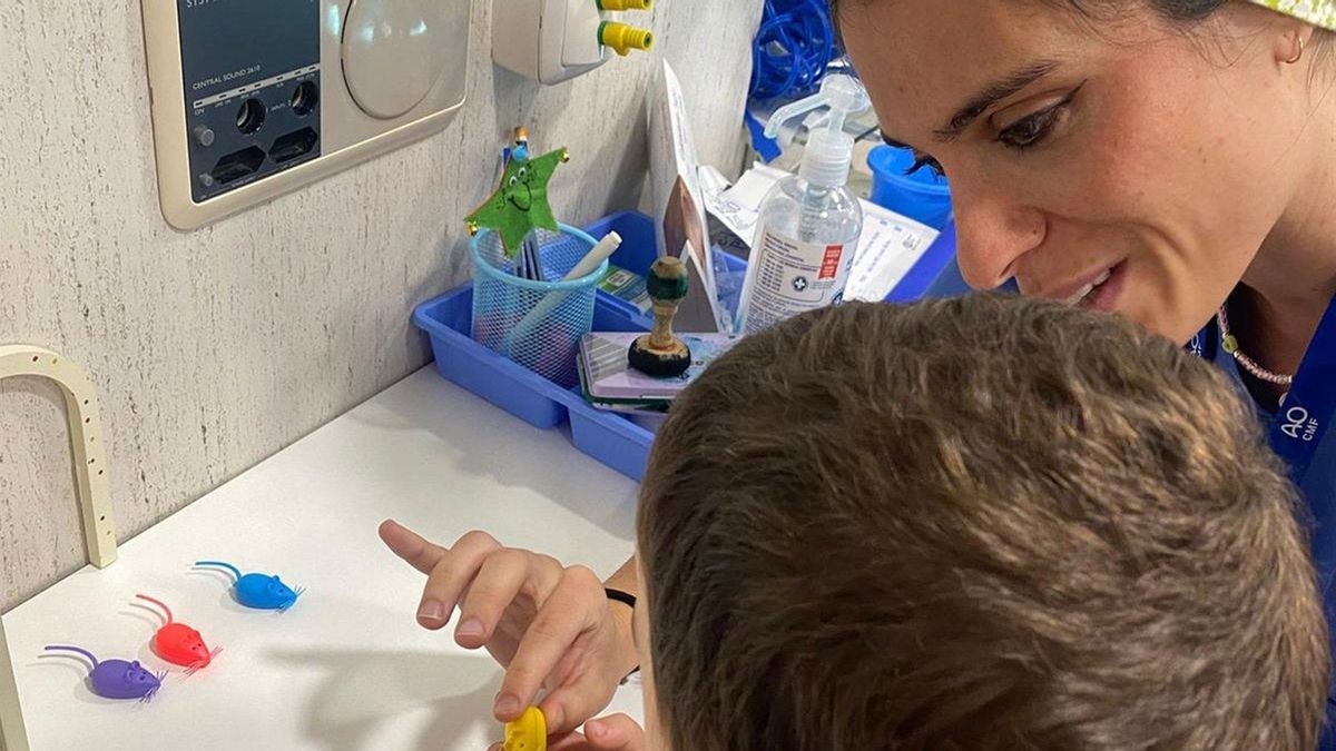 Profesional del servicio de Cirugía Oral y Maxilofacial acompaña al niño y le muestra la cajita donde guardar su diente.