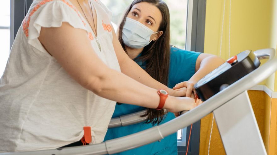 Una paciente realiza ejercicios en la cinta con el apoyo de una profesional.