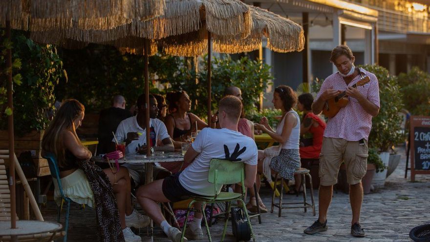 Consumidores en terrazas junto a un artista en Barcelona