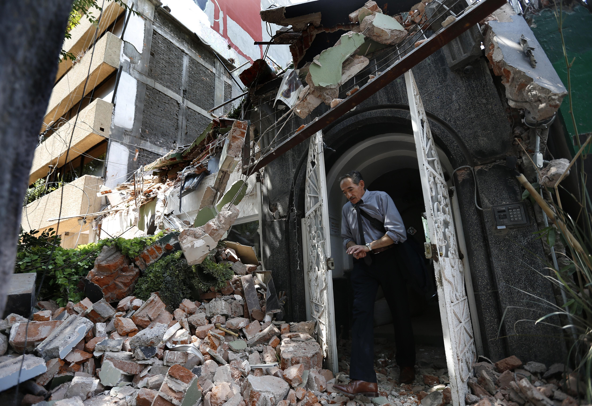 Un hombre camina hacia fuera de la puerta un edificio derrumbado tras el terremoto, en el barrio mexicano de la Condesa, en Ciudad de México.