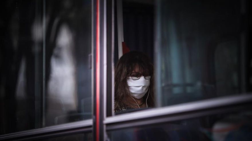 Una mujer con mascarilla usa un autobús público.