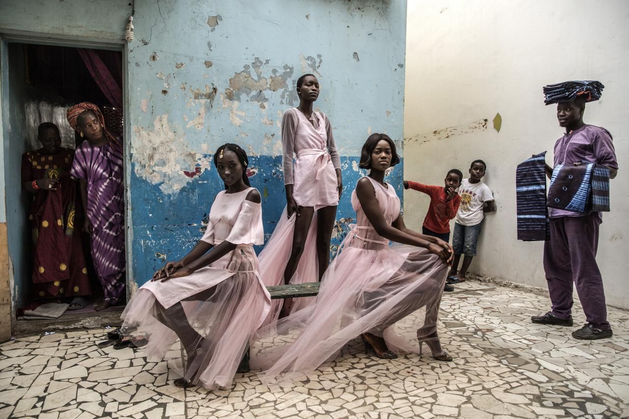 'Dakar Fashion', ganadora del primer premio en la categoría 'Retratos'. Diarra Ndiaye, Ndeye Fatou Mbaye y Mariza Sakho visten atuendos del diseñador Adama Paris, en el barrio de Medina en Dakar, la capital senegalesa, mientras los curiosos residentes observan.