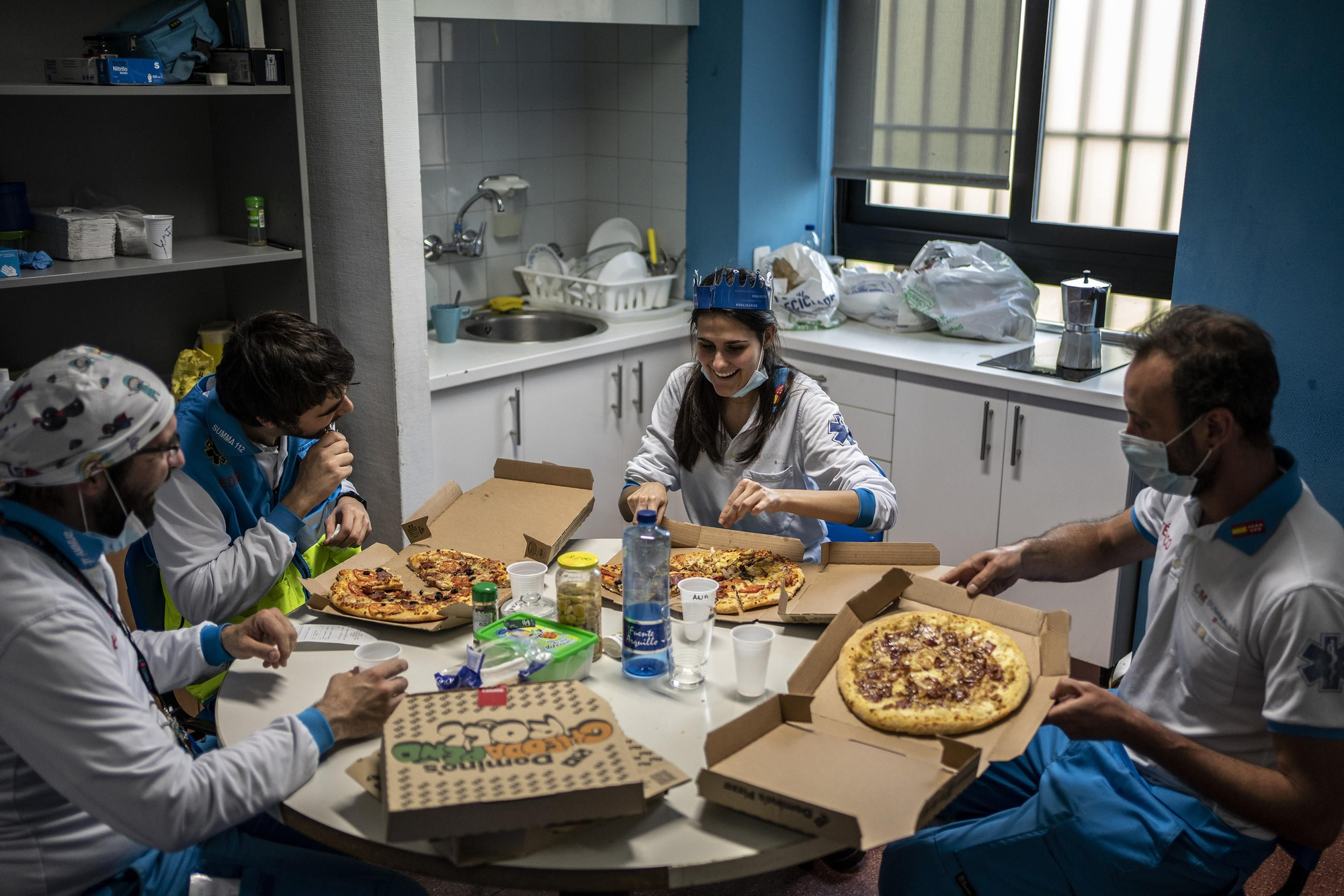 Después de un intento frustrado para comer por la llamada de una emergencia, este equipo de la UVI-8 pudo parar brevemente para comer unas pizzas en su base de Aluche. Antes de terminar les llamaron para otra intervención.  En la imagen Javier de prensa del SUMMA, Carlos Rubio, médico, Ana Moreno, enfermera, y José Sevillano, técnico en emergencias.