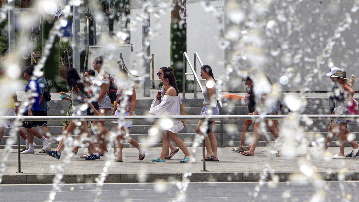 Varias personas pasan ante una fuente en una calle de la ciudad de Alicante