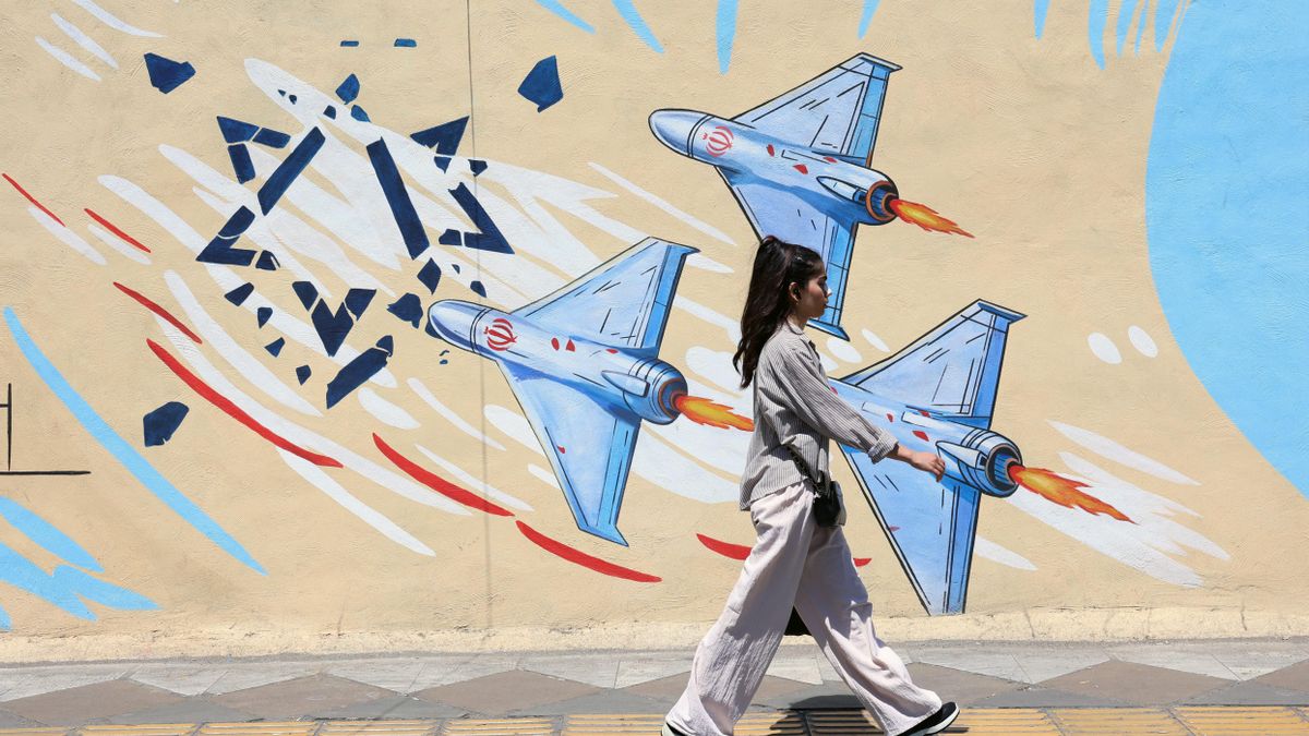 Una joven iraní pasa junto a un mural antiisraelí en una calle de Teherán, Irán, el lunes 8 de junio. EFE/EPA/ABEDIN TAHERKENAREH