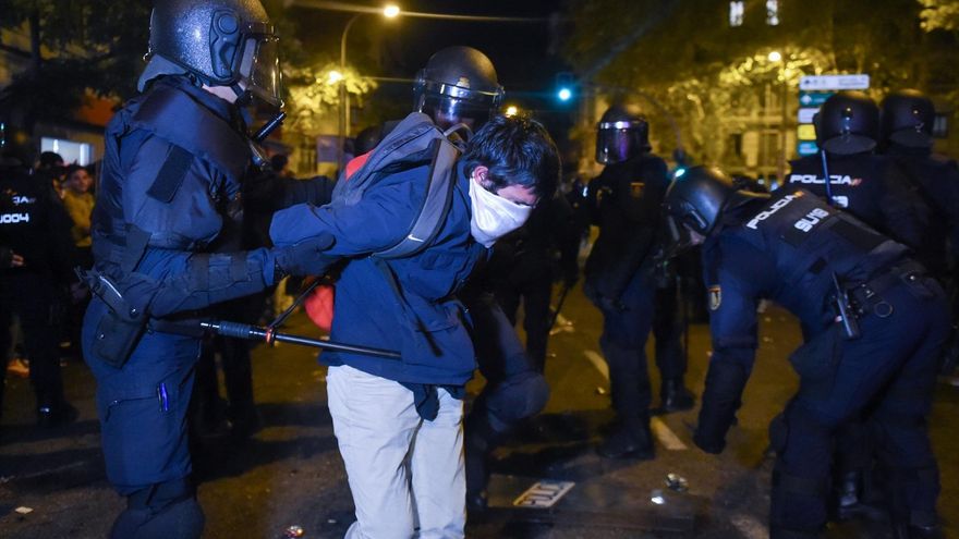 Un joven embozado es detenido por varios agentes de policía, durante una manifestación contra la amnistía frente a la sede del PSOE en Ferraz, a 18 de noviembre de 2023