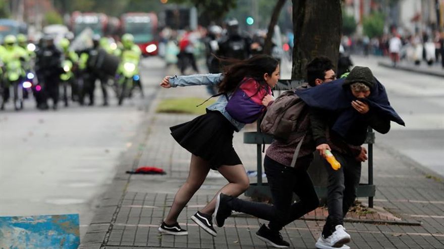 Un grupo de jóvenes fue registrado este viernes al cruzar una calle al intentar huir de los gases lacrimógenos, durante el segundo día de protestas en contra del Gobierno del presidente de Colombia, Ivan Duque, en Bogotá (Colombia).