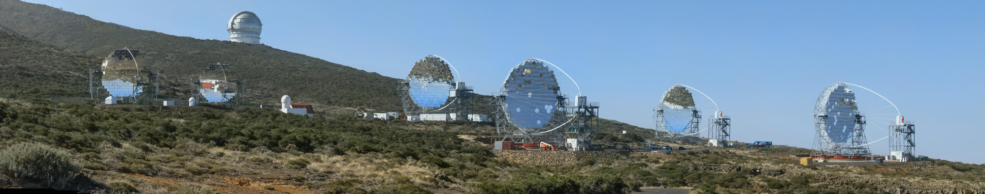 Los dos telescopios MAGIC  (I) y los cuatro telescopios de gran tamaño (LST)  de la Red Cherenkov en el Observatorio  del Roque de los Muchachos. Al fondo, el Gran Telescopio Canarias.