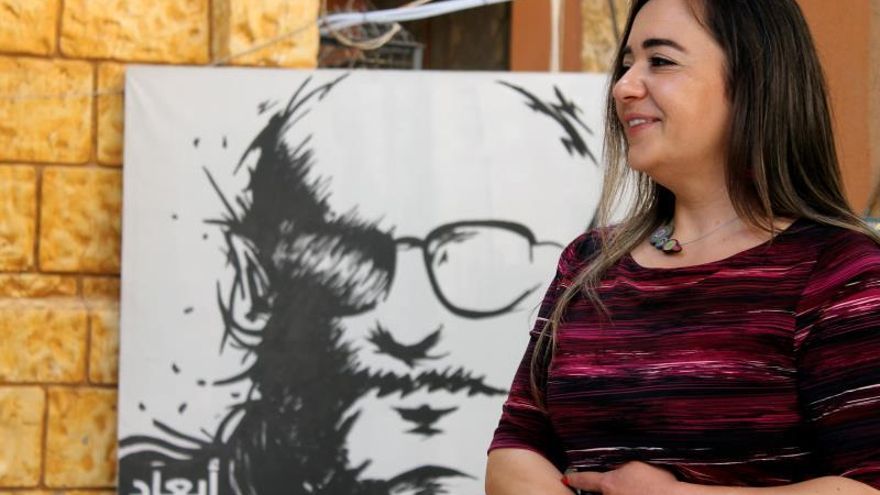 La directora de la ONG Abaad, Ghida Anani, en su oficina en Beirut, Líbano, y frente a una de sus campañas en la que muestran retratos robot de violadores.