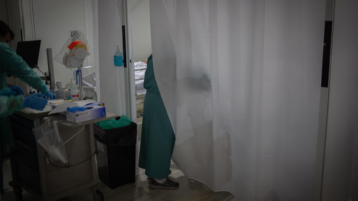 Un sanitario visita a uno de los enfermos ingresado en uno de los boxes de la Unidad de Cuidados Intensivos.
