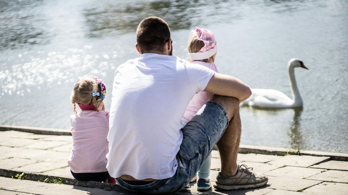 Un padre con sus hijas frente al lago