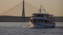Imagen del ferry cruzando el río, con el puente internacional al fondo.