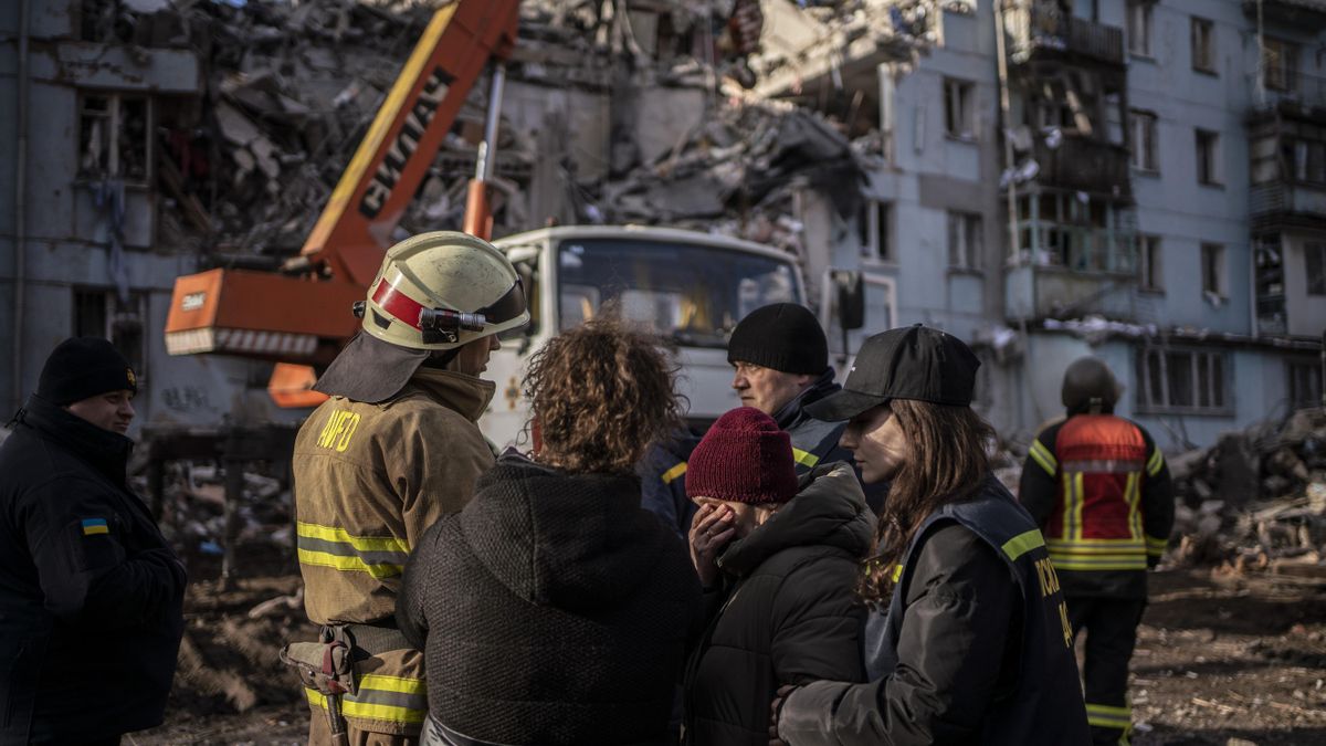 Los familiares de una persona desaparecida en el edificio bombardeado en Zaporiyia este jueves hablan con los equipos de rescate