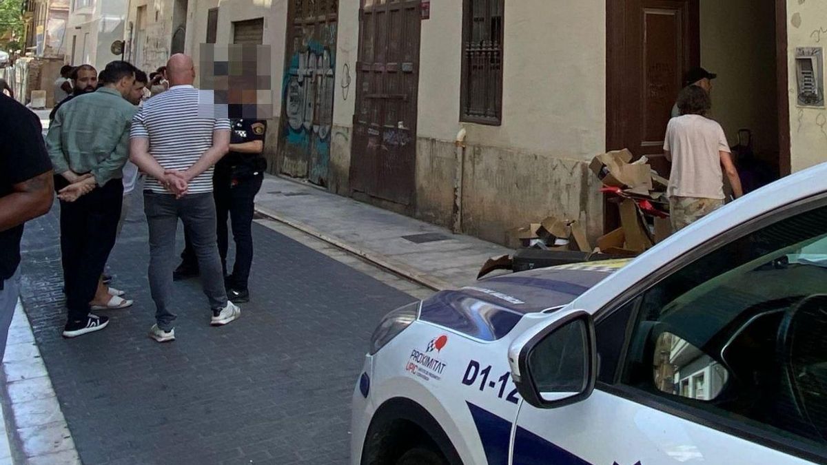 La Policía Local identifica a un grupo de personas ante la puerta del edificio.