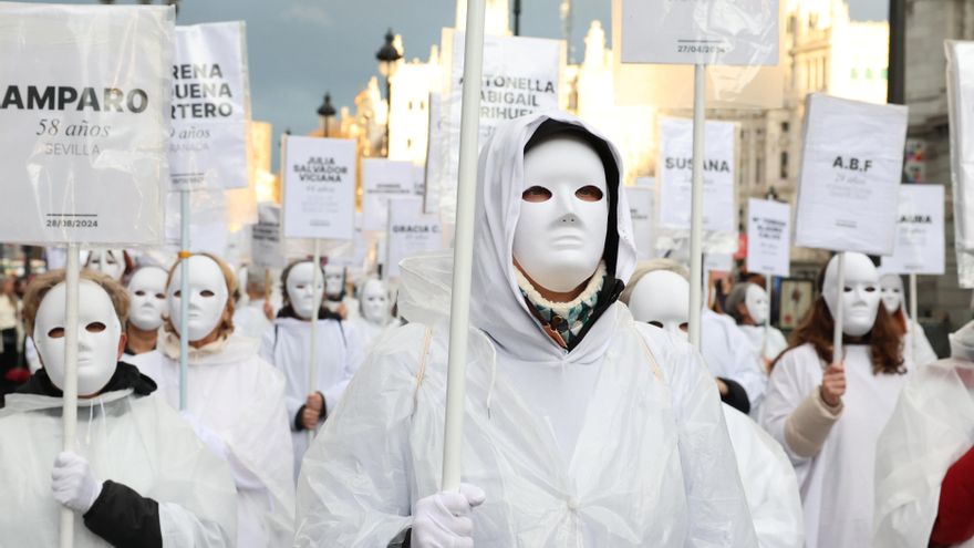 Un grupo de mujeres vestidas de blanco y con máscaras porta los nombres de algunas de las mujeres víctimas de violencia machista de los últimos años durante la manifestación de Madrid.
