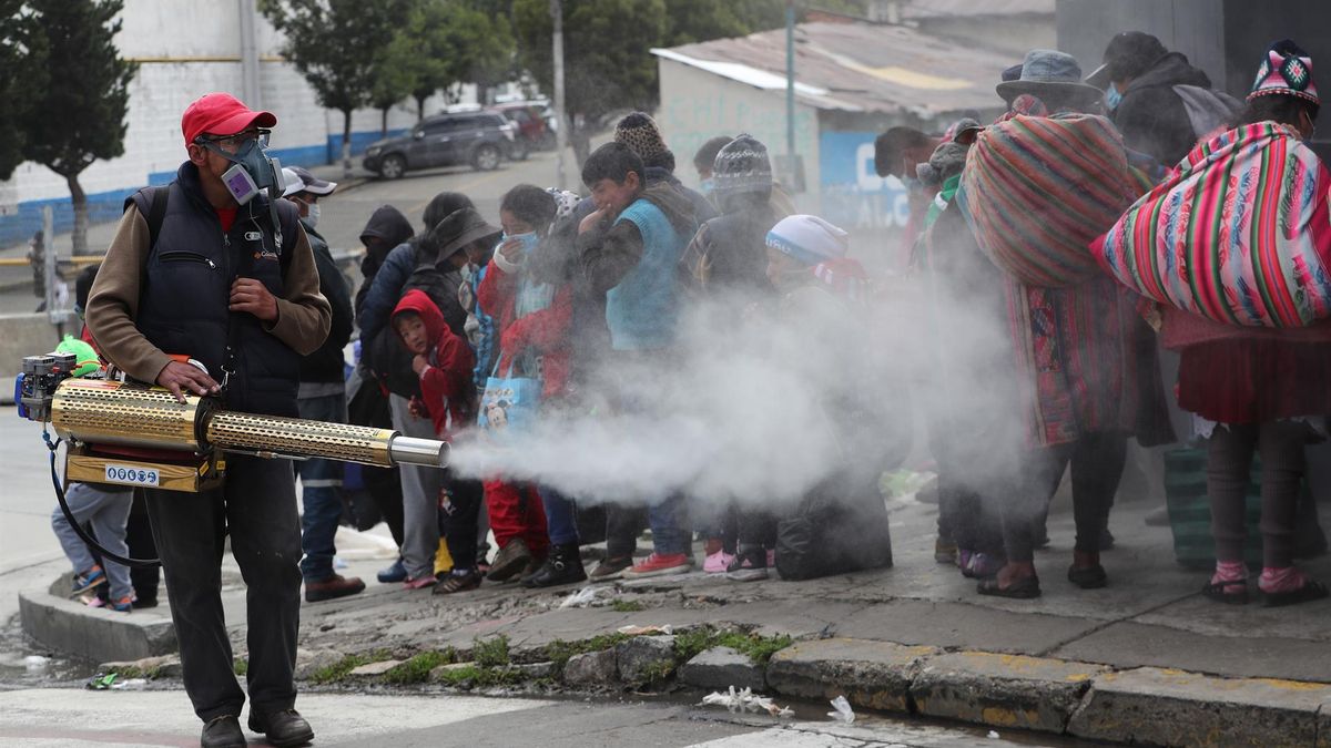 Un voluntario de la Iglesia Monte de Oración realiza la desinfección y fumigación contra la COVID-19 en las filas de ciudadanos que esperan los alimentos, vestimenta y regalos de la campaña de fin de año "El buen Samaritano", hoy en La Paz (Bolivia).
