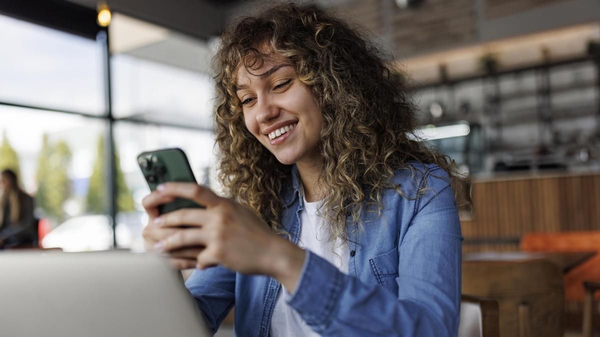 Una mujer utiliza un teléfono móvil y un ordenador portátil