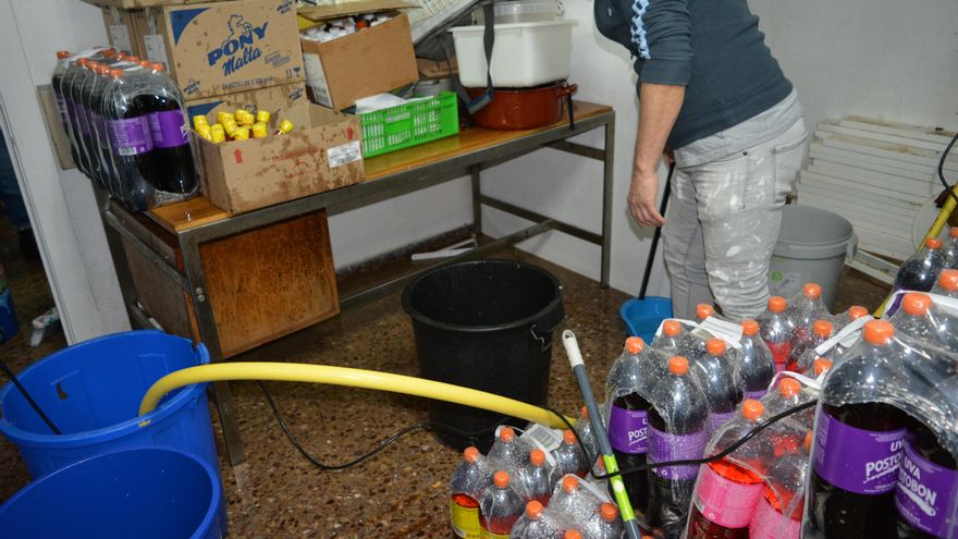 Un vecino ayuda a Andrea a Sacar agua de su tienda de alimentación