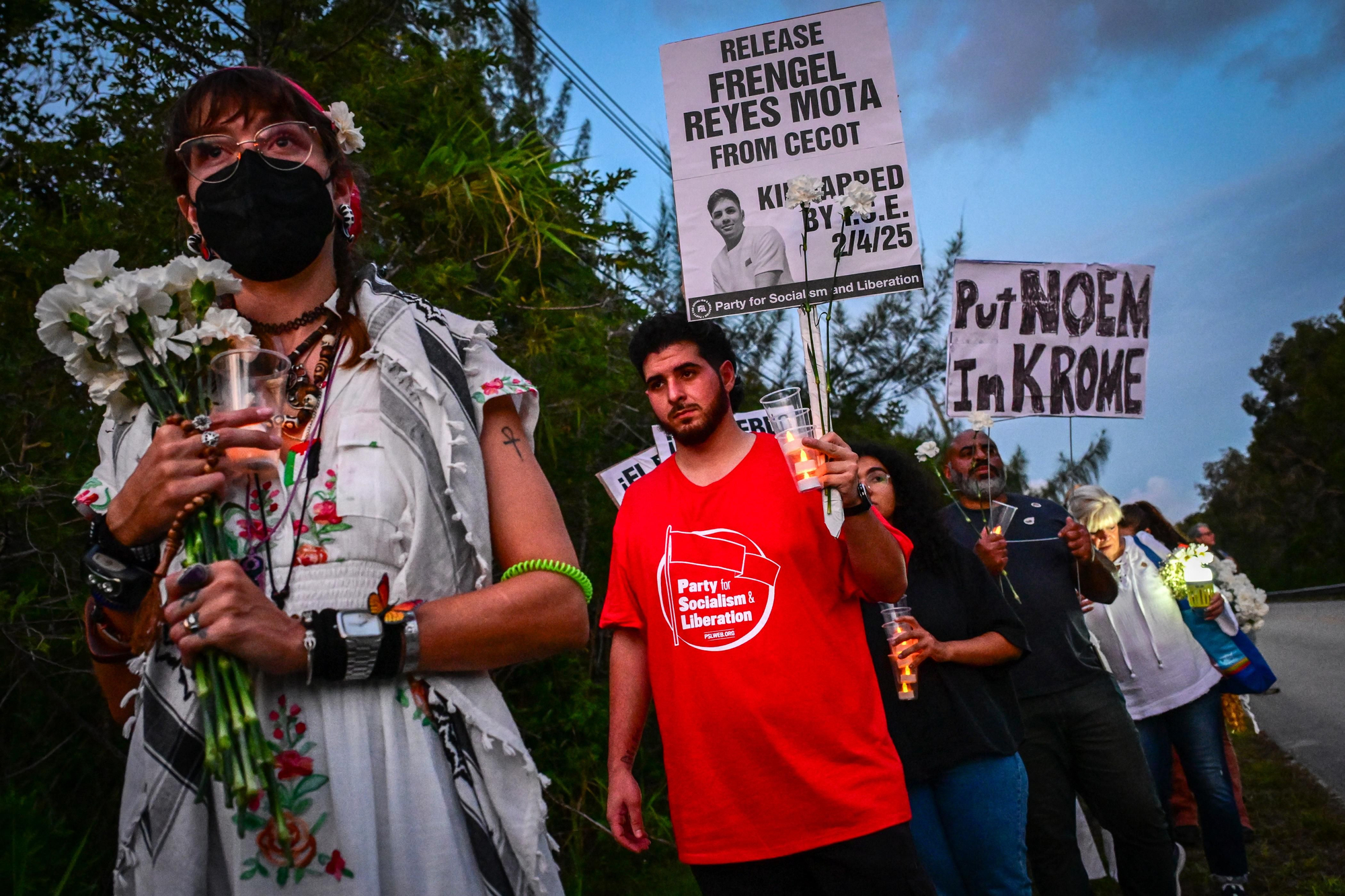 Personas sostienen velas y carteles con la leyenda "Meter a Noem en Krome" durante una vigilia en protesta contra la detención y las deportaciones masivas del Servicio de Inmigración y Control de Aduanas de Estados Unidos (ICE) frente al Centro de Detención de Krome en Miami el 24 de mayo de 2025.